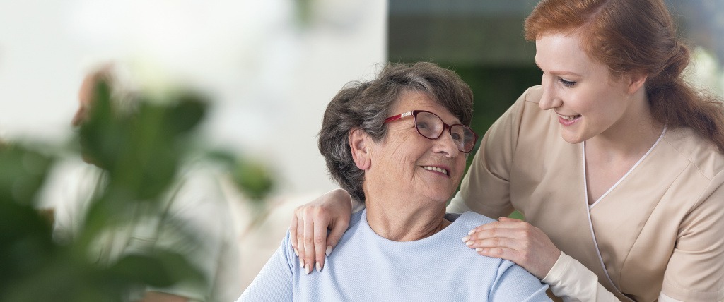 caregiver with her hands on the shoulders of a senior woman
